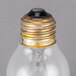 A close up of a Satco clear rough service light bulb with a gold cap.