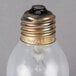 A close up of a Satco 60 watt clear incandescent light bulb with a metal cap.