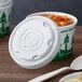 A white EcoChoice plastic container with a vented lid on a cup of soup.