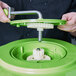 A person using a green and white Choice salad spinner cover with handle.