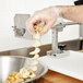 A person in gloves uses a Nemco Ribbon Fry Cutter to cut a spiral potato.