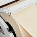 A Bulman gray steel paper dispenser with a roll of paper on it.