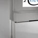 A close-up of a silver metal Avantco refrigerator with a metal hinge kit on it.