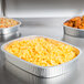 A Durable Packaging silver aluminum tray with a dome lid containing macaroni and cheese on a table.