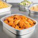 A Durable Packaging silver aluminum medium entree pan with a dome lid filled with food on a table.