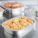 A Durable Packaging silver aluminum tray with a dome lid containing rice and vegetables.