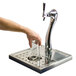 A hand pouring a glass of water into a chrome Micro Matic tap tower.