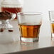 Two Libbey Gibraltar rocks glasses filled with brown liquid on a counter.