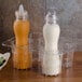 A clear plastic container with GET CLIPS-PLAIN-PC-CL Salad Dressing Label Clips on bottles of mustard and ranch dressing.