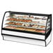 A True curved glass dry bakery display case filled with a variety of pastries.