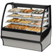 A True curved glass stainless steel dry bakery display case on a counter with different types of pastries.