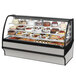 A True curved glass refrigerated bakery display case filled with various cakes.