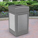 A gray Commercial Zone StoneTec waste receptacle with Ashtone panels on a brick surface.