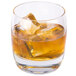 A Reserve by Libbey Symmetry old fashioned glass of amber liquid with ice cubes.
