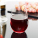 A close-up of a Reserve by Libbey Renaissance stemless wine glass filled with red wine on a table.