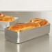 Two loaves of bread in Vollrath aluminum bread loaf pans on a counter.