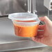 A hand microwaving a ChoiceHD translucent plastic deli container with food inside.