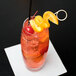 A Reserve by Libbey highball glass filled with an orange drink, ice, and cherries with a straw.
