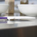 A white surface with a purple and white Rubbermaid high temperature silicone spatula.