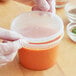 A gloved hand holding a ChoiceHD translucent plastic deli container with a lid.