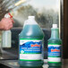 A hand holding a green bottle of Noble Chemical Reflect Super Concentrated Window Cleaner.