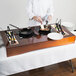 A chef cooking food on a Tablecraft copper induction station on a table.