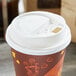 A Choice white paper cup lid with a hinged tab over a paper cup.