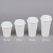 A row of white Choice paper cups with white hinged travel lids.