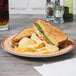 A sandwich and chips on a Kanello ivory melamine plate with an orange rim.