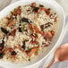 A bowl of organic brown long grain rice with mushrooms and a spoon.