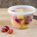 A Pactiv translucent plastic deli container filled with fruit, including red grapes.