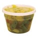 A Pactiv translucent plastic deli container filled with soup with vegetables.