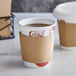 An EcoChoice coffee cup sleeve wrapped around a brown coffee cup.