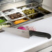 A knife on a cutting board with food in containers inside a Turbo Air sandwich prep table.