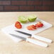A Choice white bar size cutting board with a knife and a lime on it.