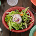 A red GET Diamond Harvest melamine bowl filled with salad on a table.