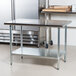 An Advance Tabco stainless steel work table with a galvanized undershelf in a professional kitchen.