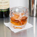 A GET stackable plastic double rocks glass filled with brown liquid on a napkin on a bar counter.