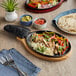 A Choice cast iron fajita skillet with food on a wooden board.