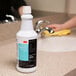 A white bottle of 3M TB Quat Disinfectant cleaner with a black and blue label on a counter.