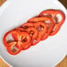 Sliced red bell peppers on a white plate using a Robot Coupe 5 Food Processor Disc Kit.