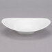 A white Reserve by Libbey Royal Rideau porcelain bowl with a curved edge on a gray surface.