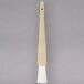 A close up of a Carlisle white Teflon bristle pastry brush with a long handle.