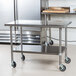 An Advance Tabco stainless steel work table with undershelf and casters.