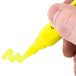 A close-up of a hand holding a Universal fluorescent yellow highlighter with a chisel tip.