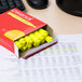 A box of Universal fluorescent yellow desk style highlighters on a desk.
