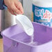A person pouring white powder into a purple container.
