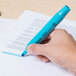 A hand using a Universal blue desk style highlighter to highlight a paper.