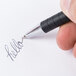 A hand writing "hello" on a piece of paper with a black Universal One Comfort Grip fine point pen.
