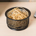 A black wire mesh basket of Universal beige rubber bands on a counter.